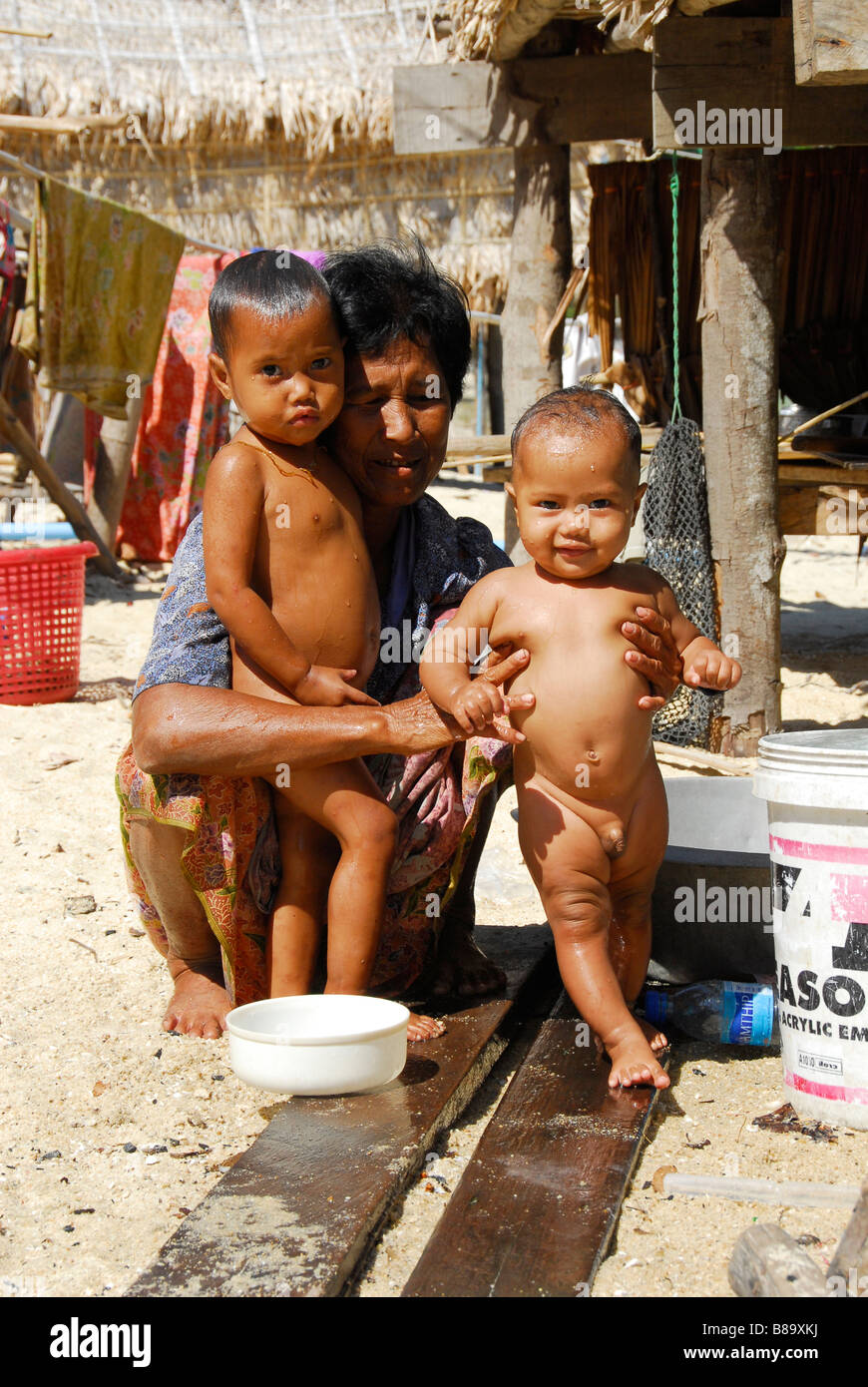 Mare Moken gypsy donna vecchia di aiutare i suoi nipoti di prendere un bagno,l'isola di Surin,PhangNga, nel sud della Thailandia. Foto Stock