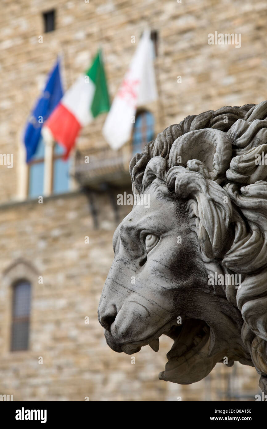 Profilo di un leone di pietra statua in Palazzo Vecchio con le bandiere degli stati in background, Firenze, Italia Foto Stock