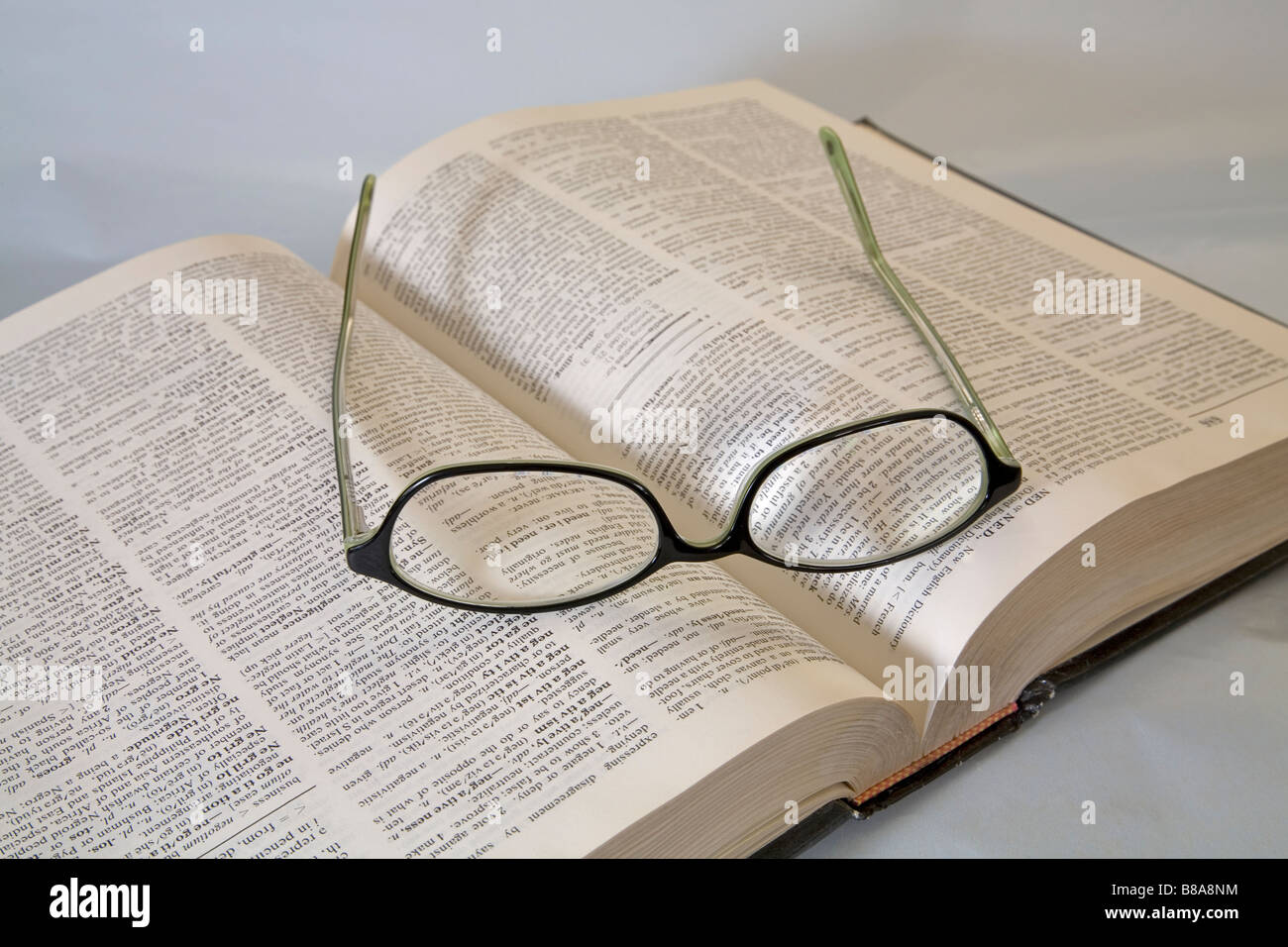 Una coppia di lettura comune occhiali o occhiali giacente su un dizionario aperto Foto Stock
