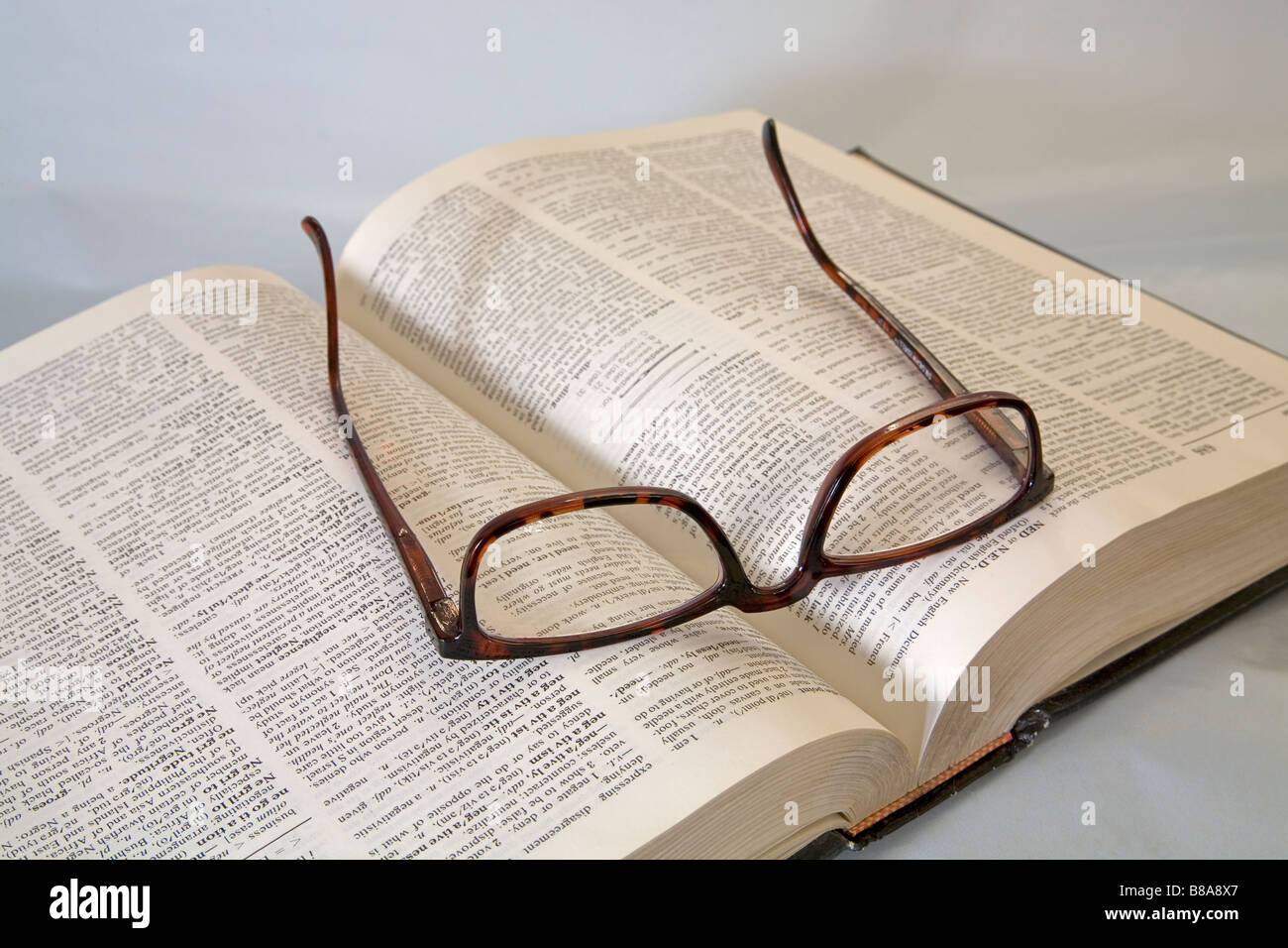 Una coppia di lettura comune occhiali o occhiali giacente su un dizionario Foto Stock