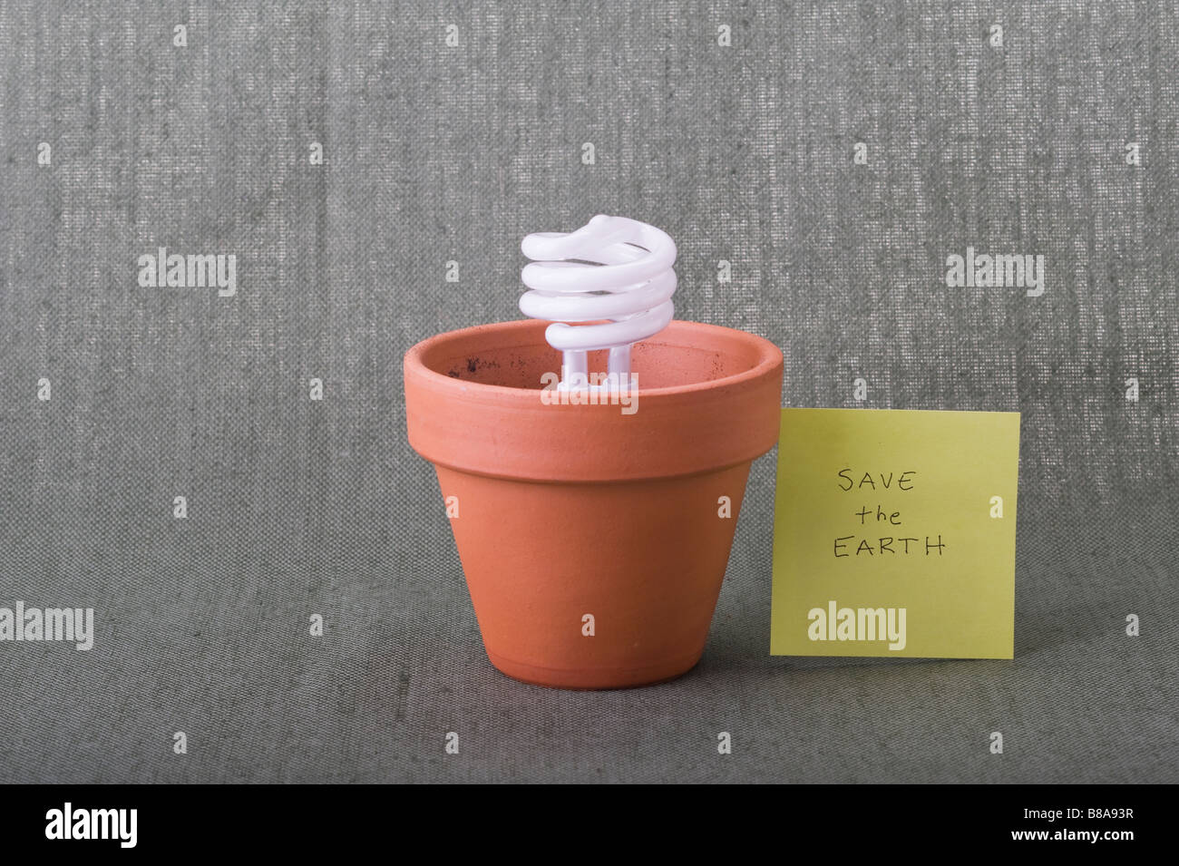 Salva la Terra eco-friendly risparmio energetico lampadina fluorescente compatta in vaso di argilla Terra giorno clima crisi ambientale responsabilità concetti. Foto Stock Salva la Terra eco-friendly risparmio energetico lampadina fluorescente compatta in vaso di argilla Terra giorno clima crisi ambientale responsabilità concetti. Foto Stock