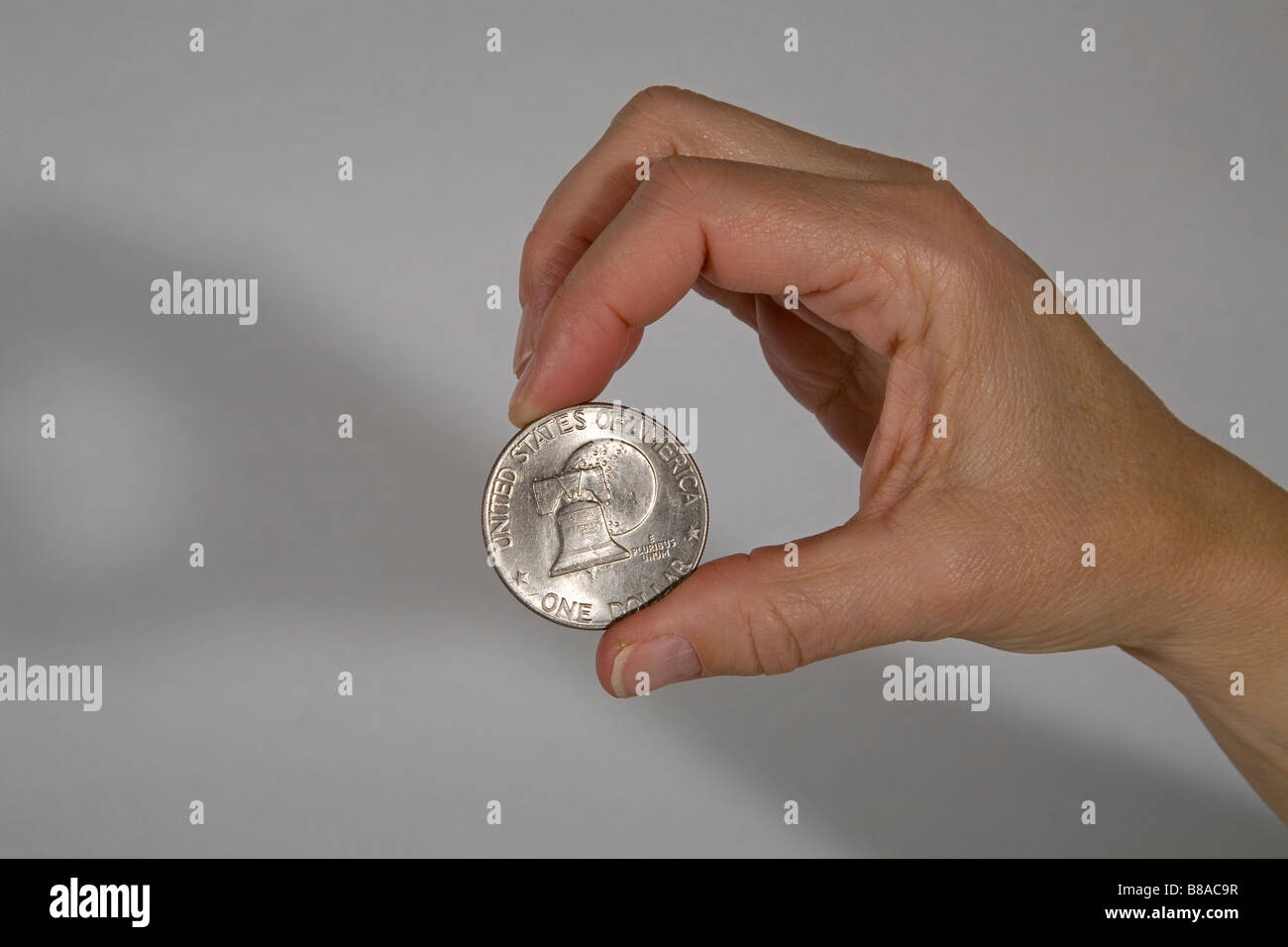 Qualcuno tenendo un noi silver dollar coin con una foto del Liberty Bell tra le dita Foto Stock