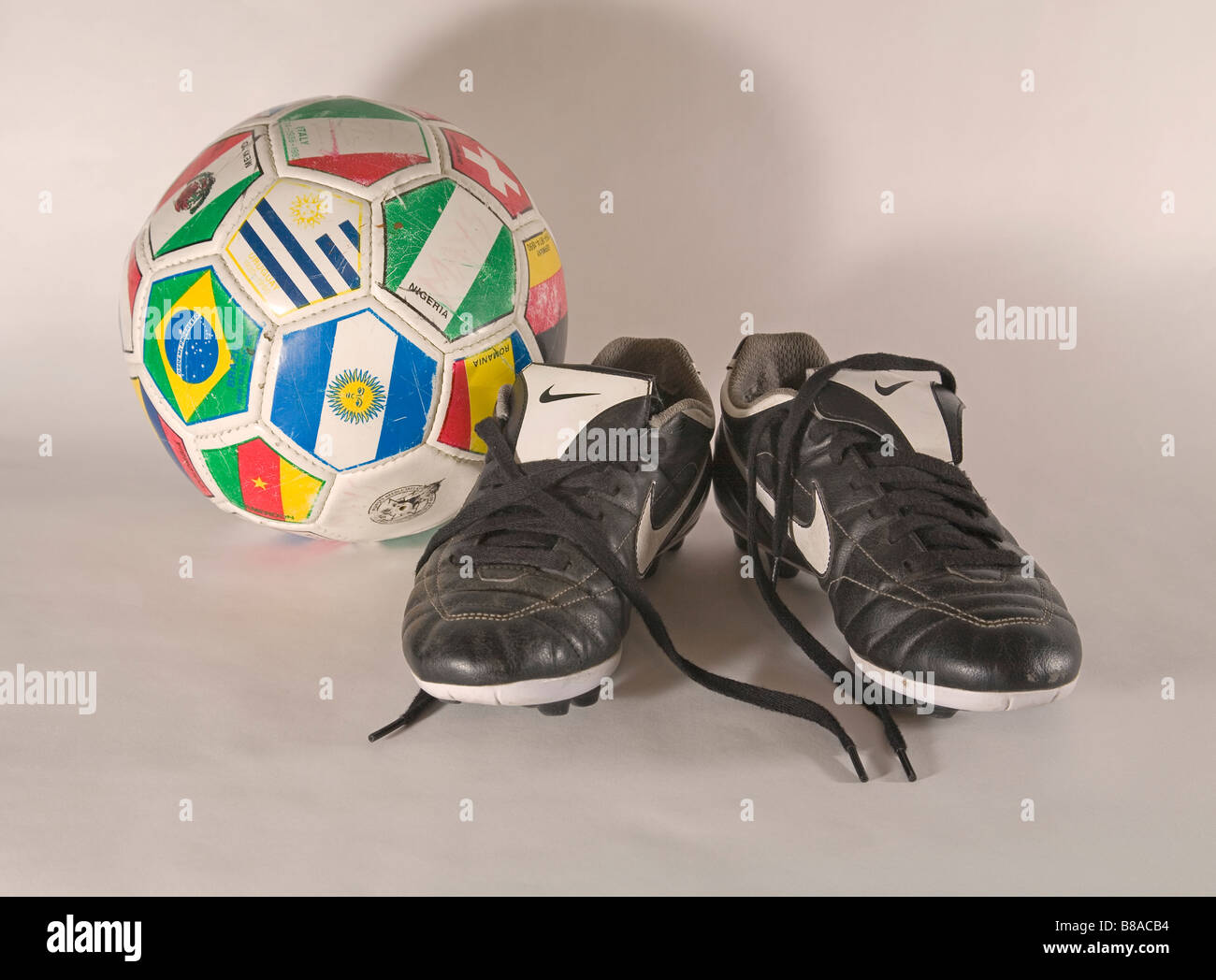 Una coppia di vecchi utilizzati soccer football scarpe e un pallone da calcio Foto Stock