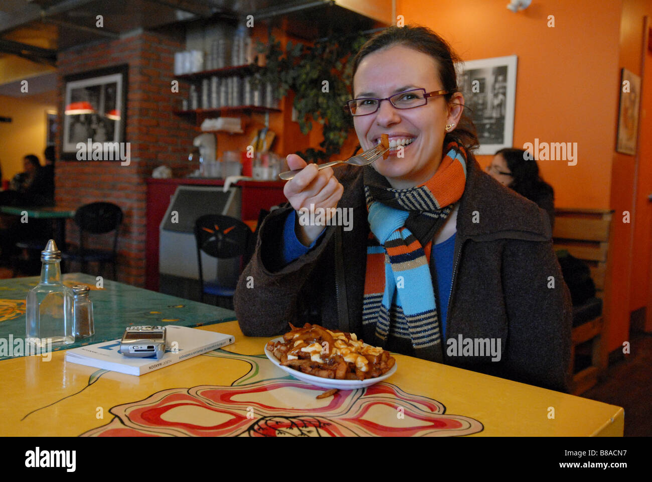 Donna di mangiare tradizionale poutine in La Banquise ristorante Quebec Montreal Canada Foto Stock