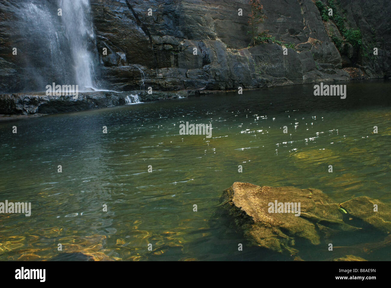 Scenario della cascata in background evidenziando una roccia in primo piano Foto Stock