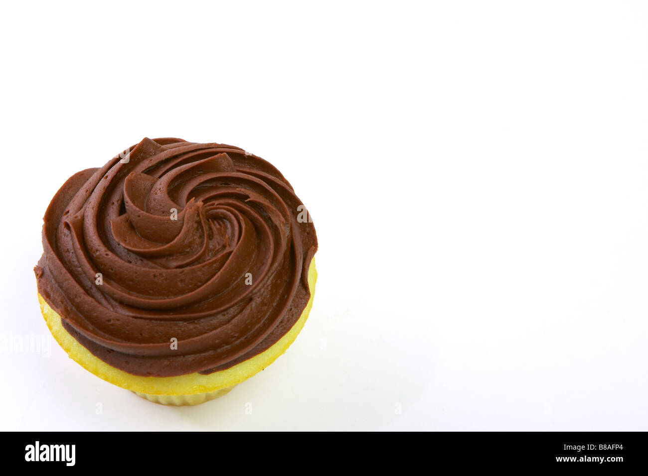 Un singolo cupcake alla vaniglia con glassa di cioccolato su uno sfondo bianco. Foto Stock