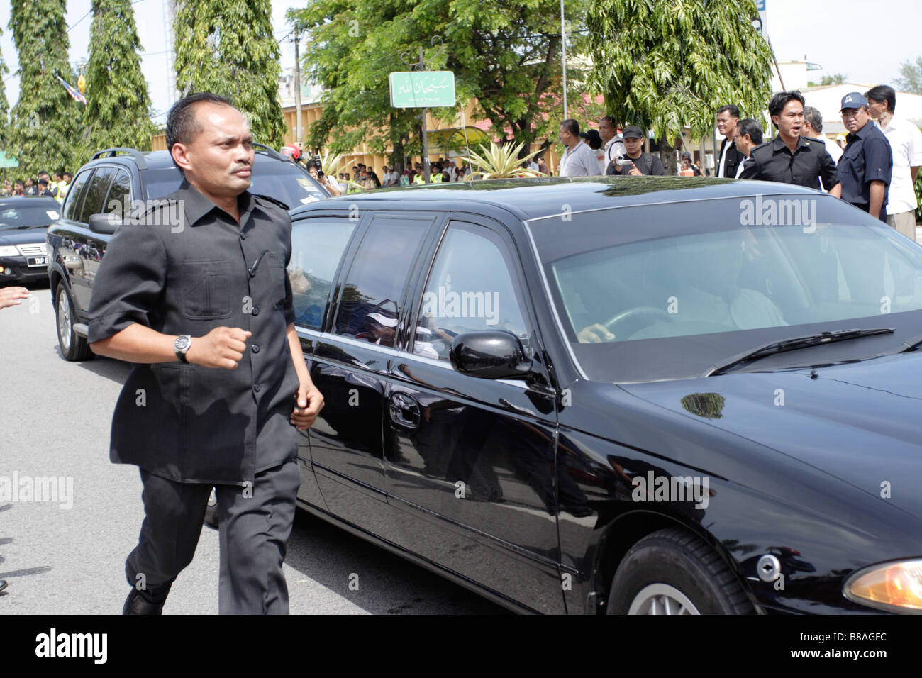 Una guardia del corpo in esecuzione accanto a un VIP auto in Malaysia. Foto Stock