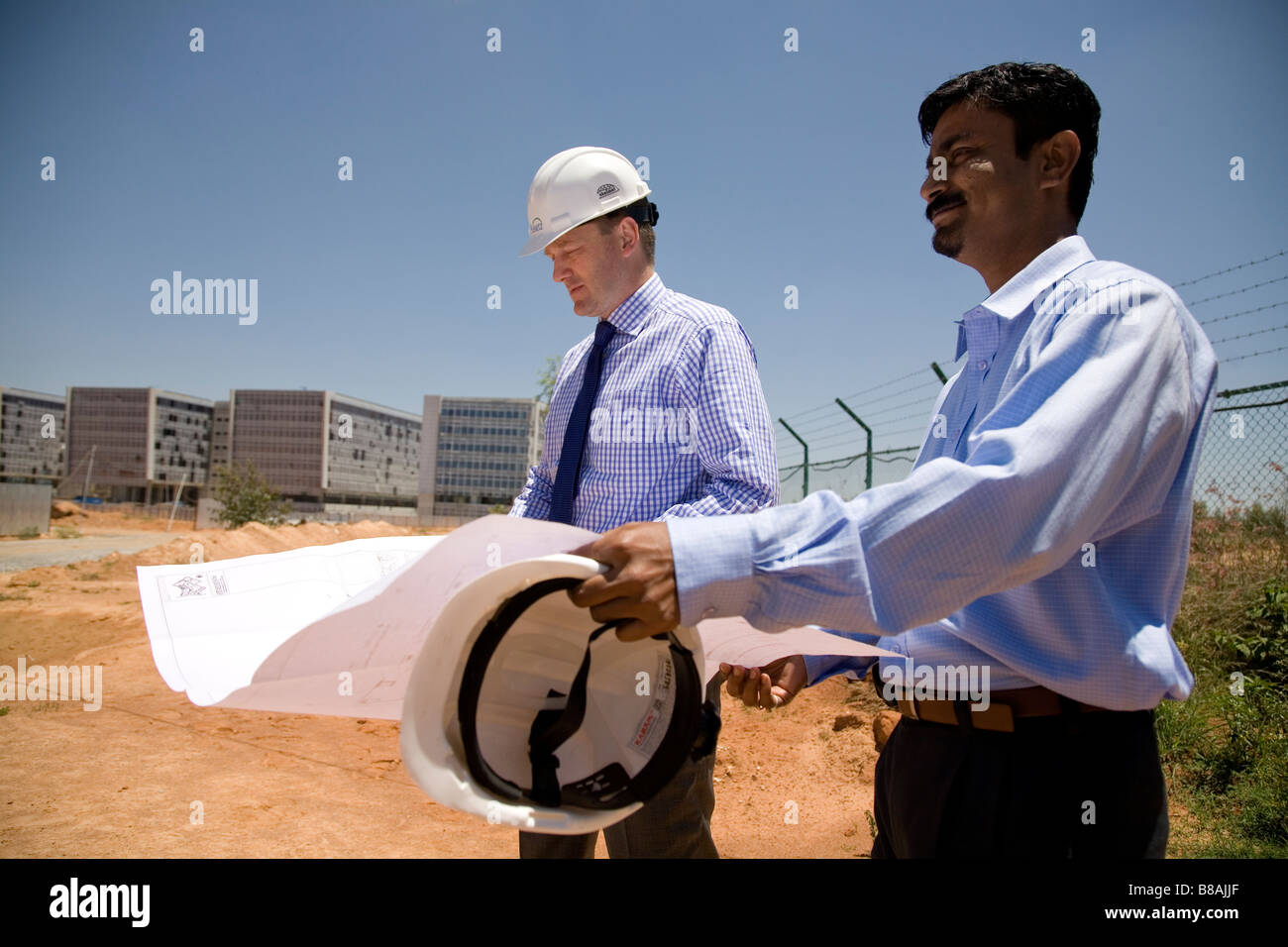 Due uomini discutere i piani in corrispondenza di un sito in costruzione a Bangalore in India. Foto Stock