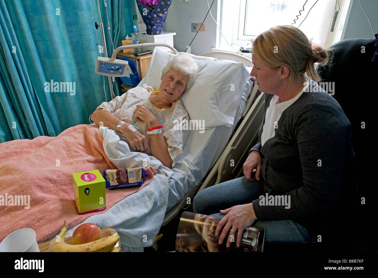 Figlia visitando madre anziana paziente nel letto di ospedale CHELTENHAM REGNO UNITO Foto Stock