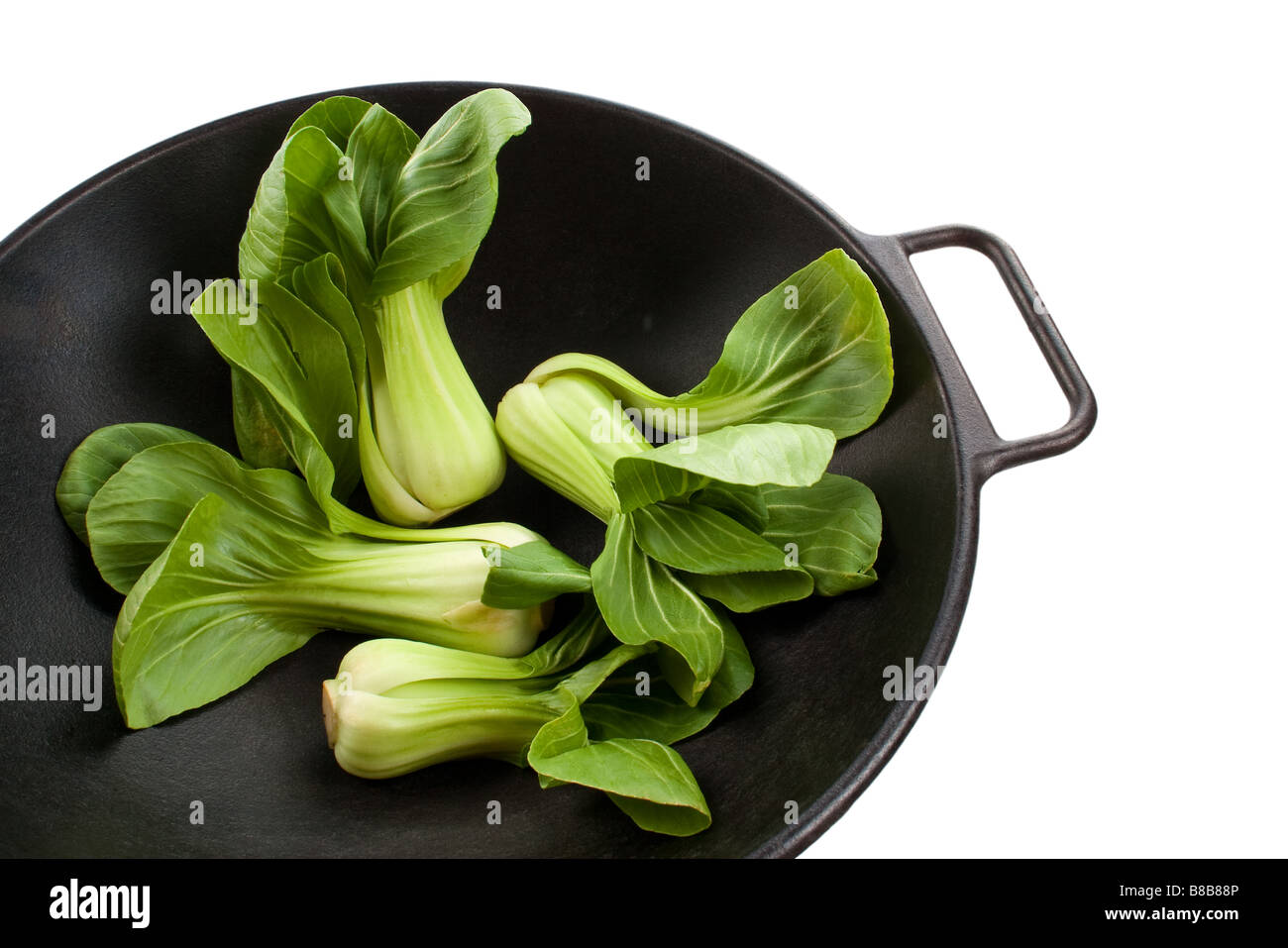 Quattro gambi di baby bok choy in un wok nero Foto Stock