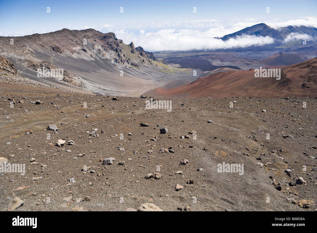 Una vista guardando verso il basso dalla sommità di Haleakala nel cratere valley con Hanakauhi picco nella distanza e la copertura nuvolosa al di sotto del Foto Stock