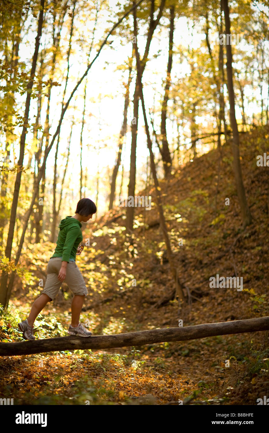 Donna in equilibrio su caduto albero tronco nel bosco Foto Stock