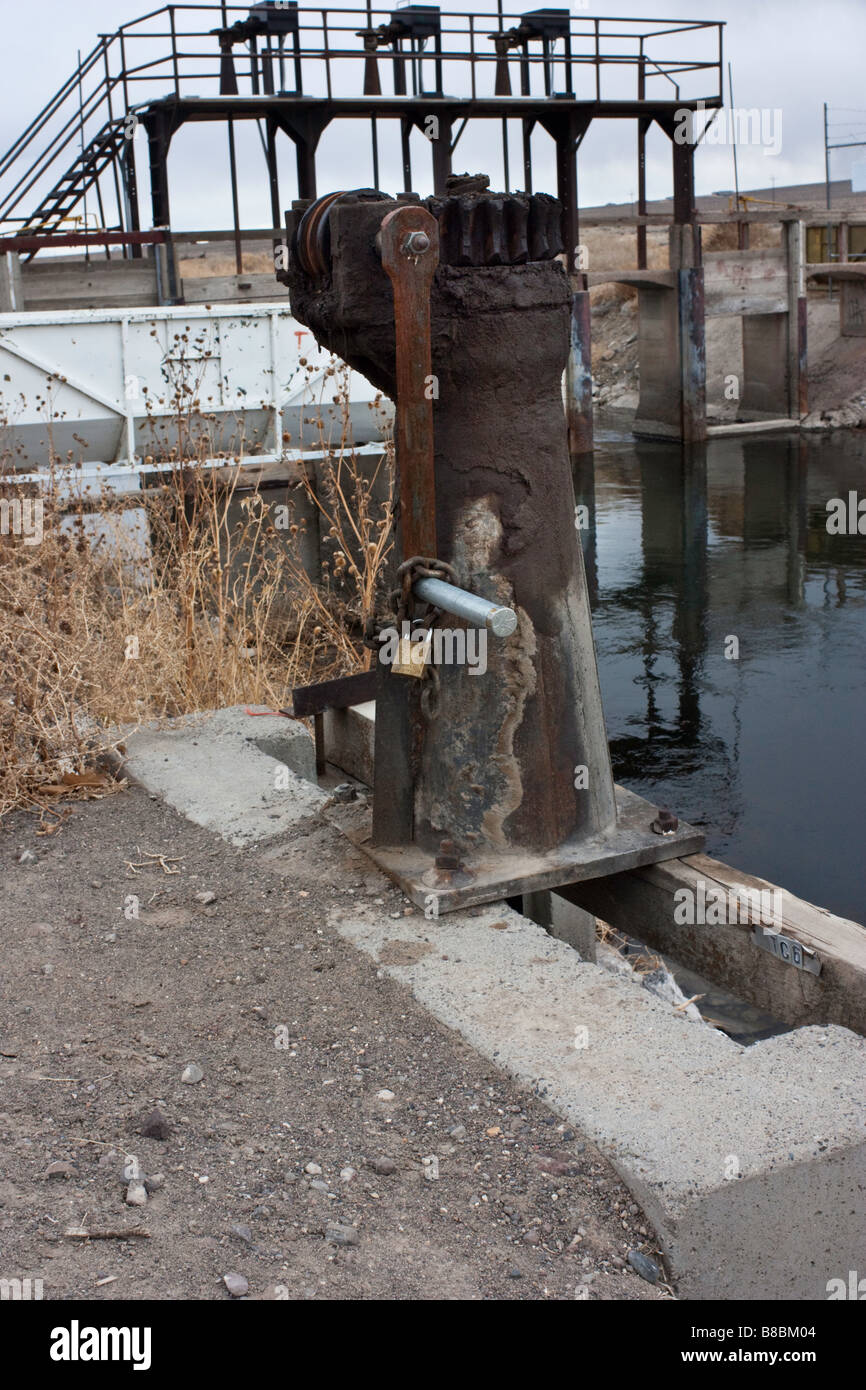 Meccanismo di trasmissione ad ingranaggi per il sollevamento di un gate di irrigazione con una diga di controllo in background in Fernley Nevada Foto Stock