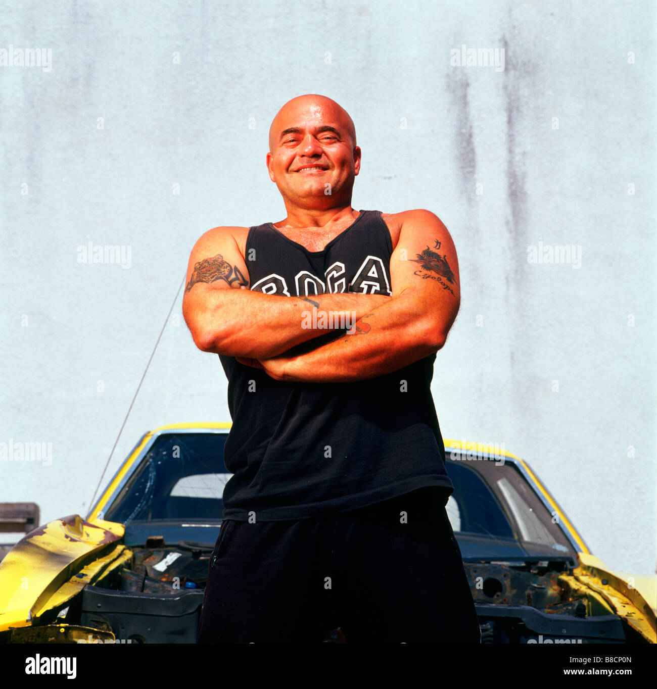 Uomo in piedi con le braccia incrociate scatafascio auto Foto Stock