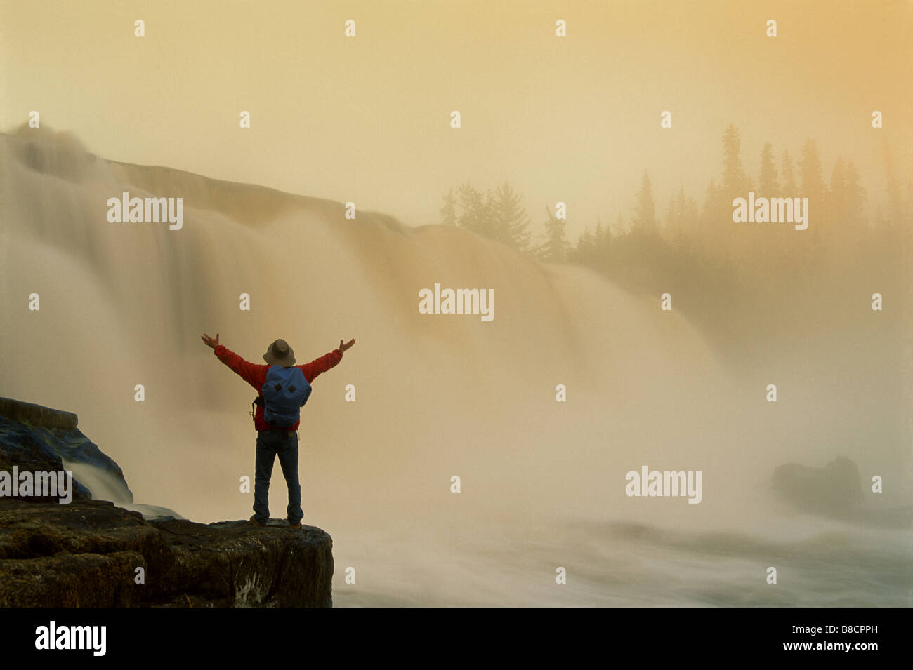 FL6466, Dave Reede; escursionista in piedi braccia tese, Cascata Bkgd, Pisew Falls heritage PP, Manitoba Foto Stock