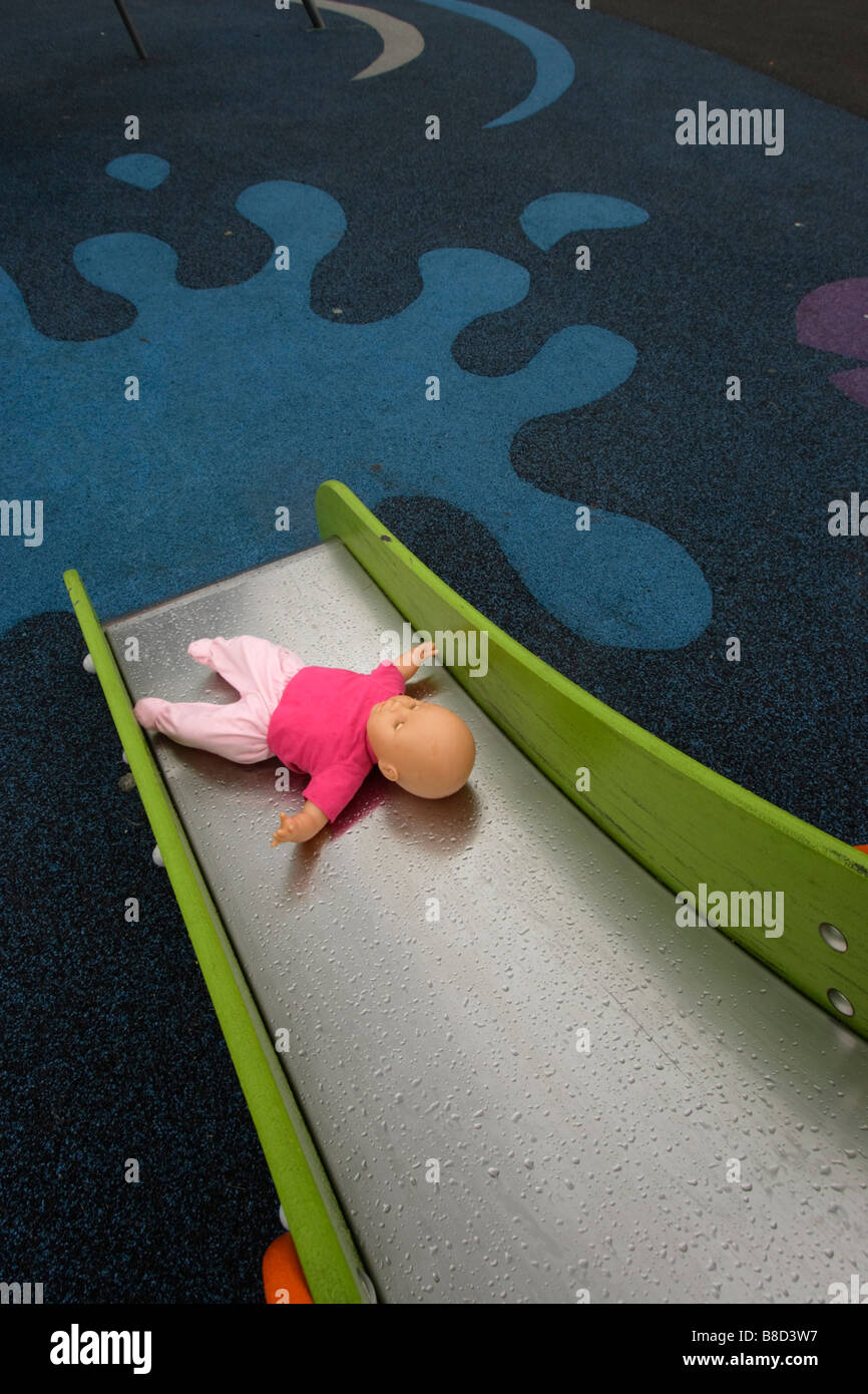 Un bambino la bambola al fondo di una diapositiva in un parco giochi. Foto Stock