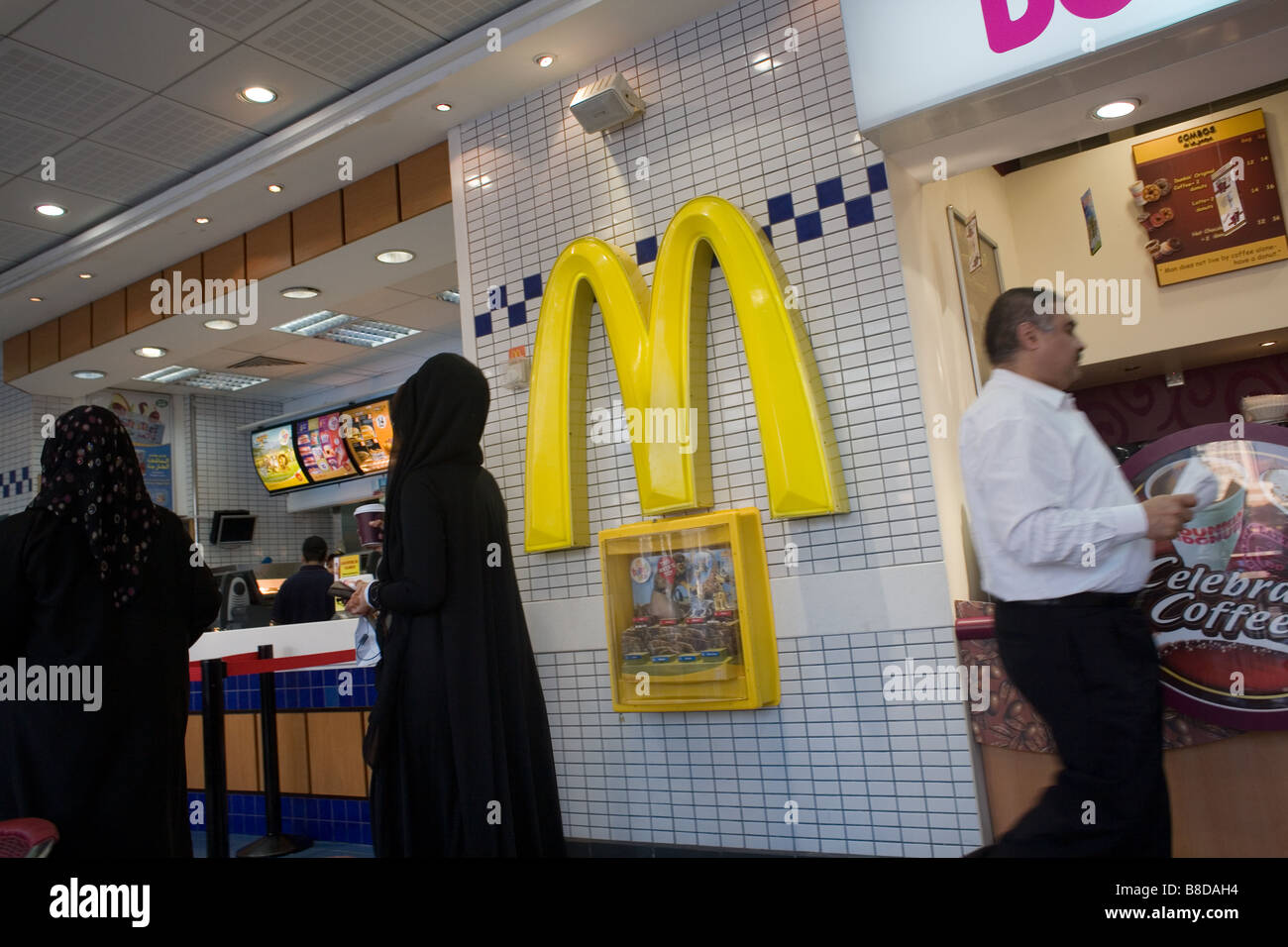 Due donne musulmane nei loro abayas lasciare un McDonalds un ristorante fast food Foto Stock