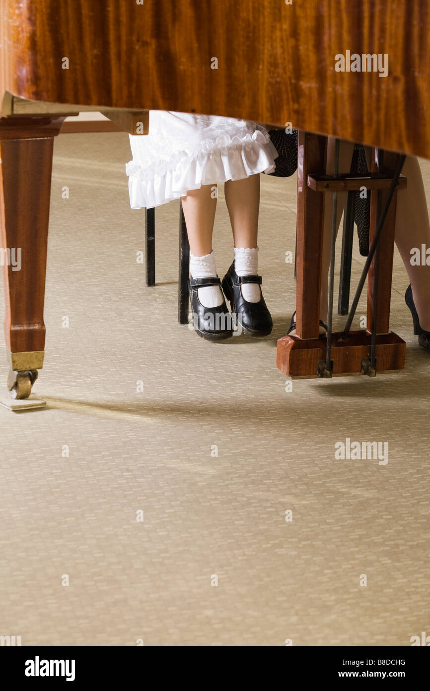 Sezione bassa del bambino e insegnante al pianoforte Foto Stock