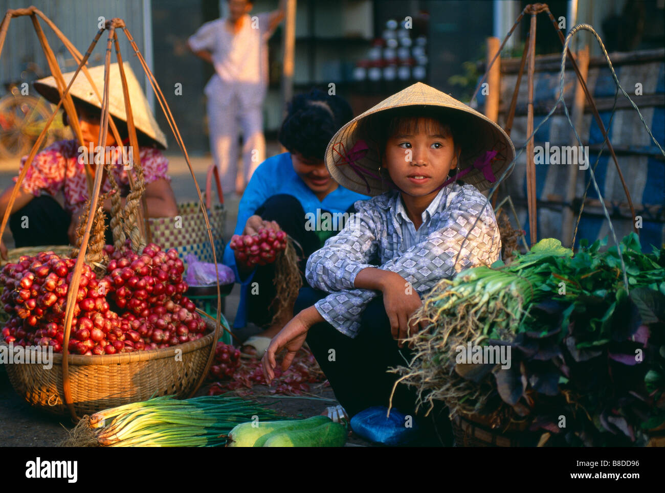 Una giovane ragazza vendere verdure a un mercato di strada, ben tre, nel delta del Mekong, Vietnam Foto Stock