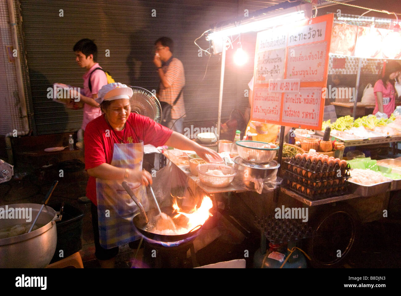 La donna la cottura stir fry tailandese cibo cinese su un mercato notturno Thanon Yaowarat road a Chinatown centrale di Bangkok in Thailandia Foto Stock