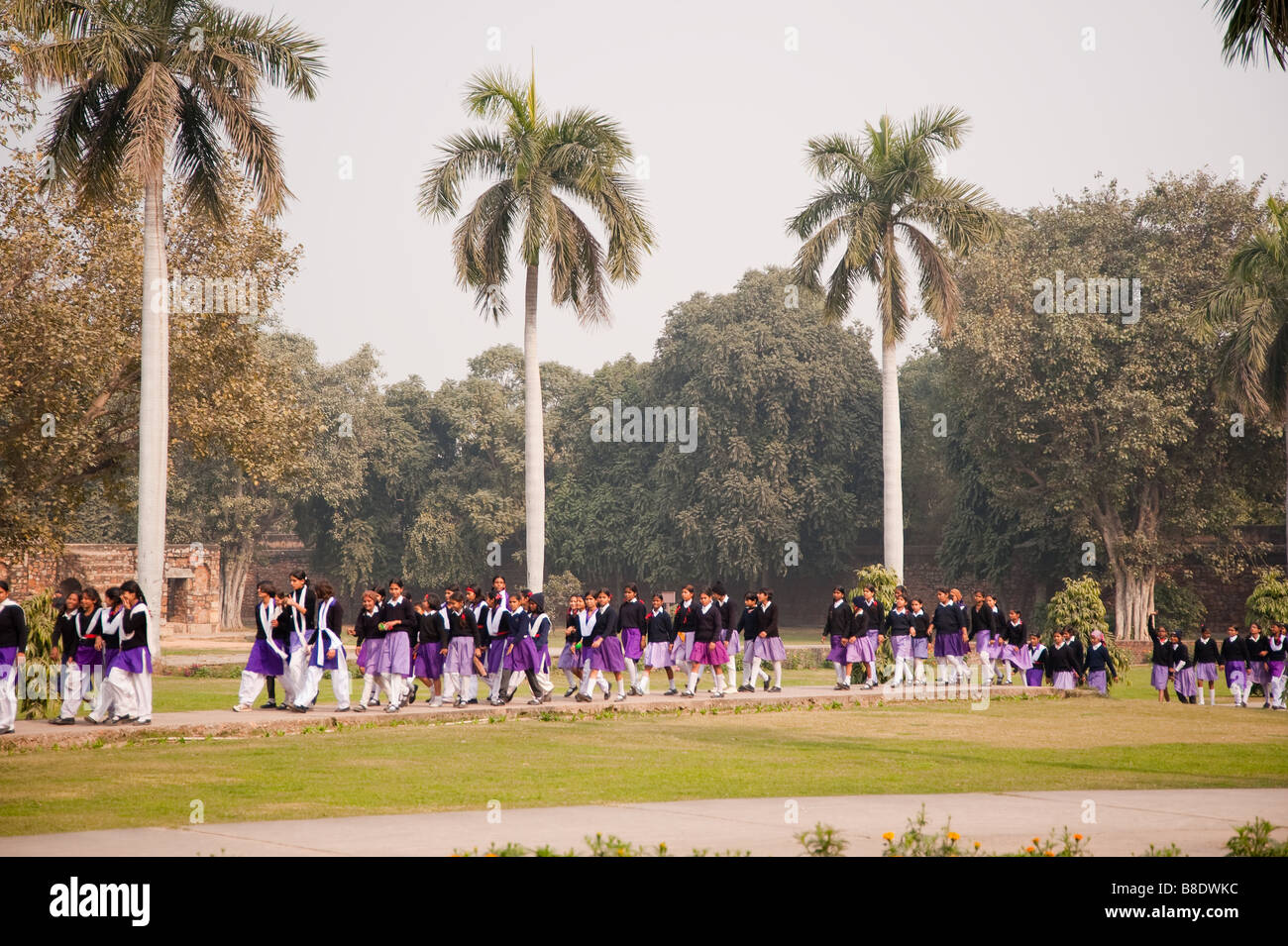 Una linea dei loro figli a scuola a piedi all'interno della tomba di Humayun complesso contro uno sfondo di alberi. Essi sono qui per una gita scolastica. Foto Stock