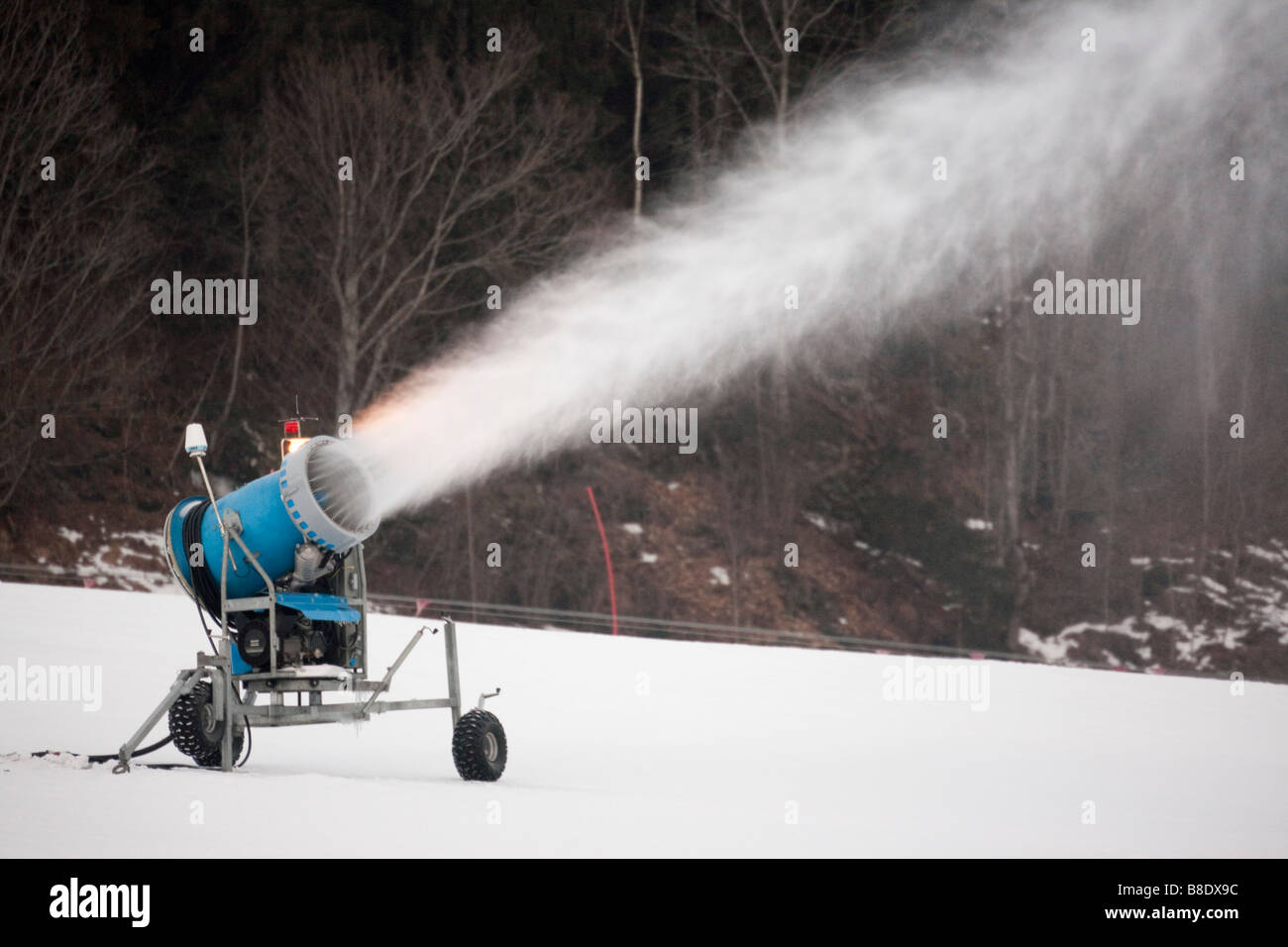 Snow making machine gettando pennacchio di neve artificiale sulla pista in località sciistica Foto Stock