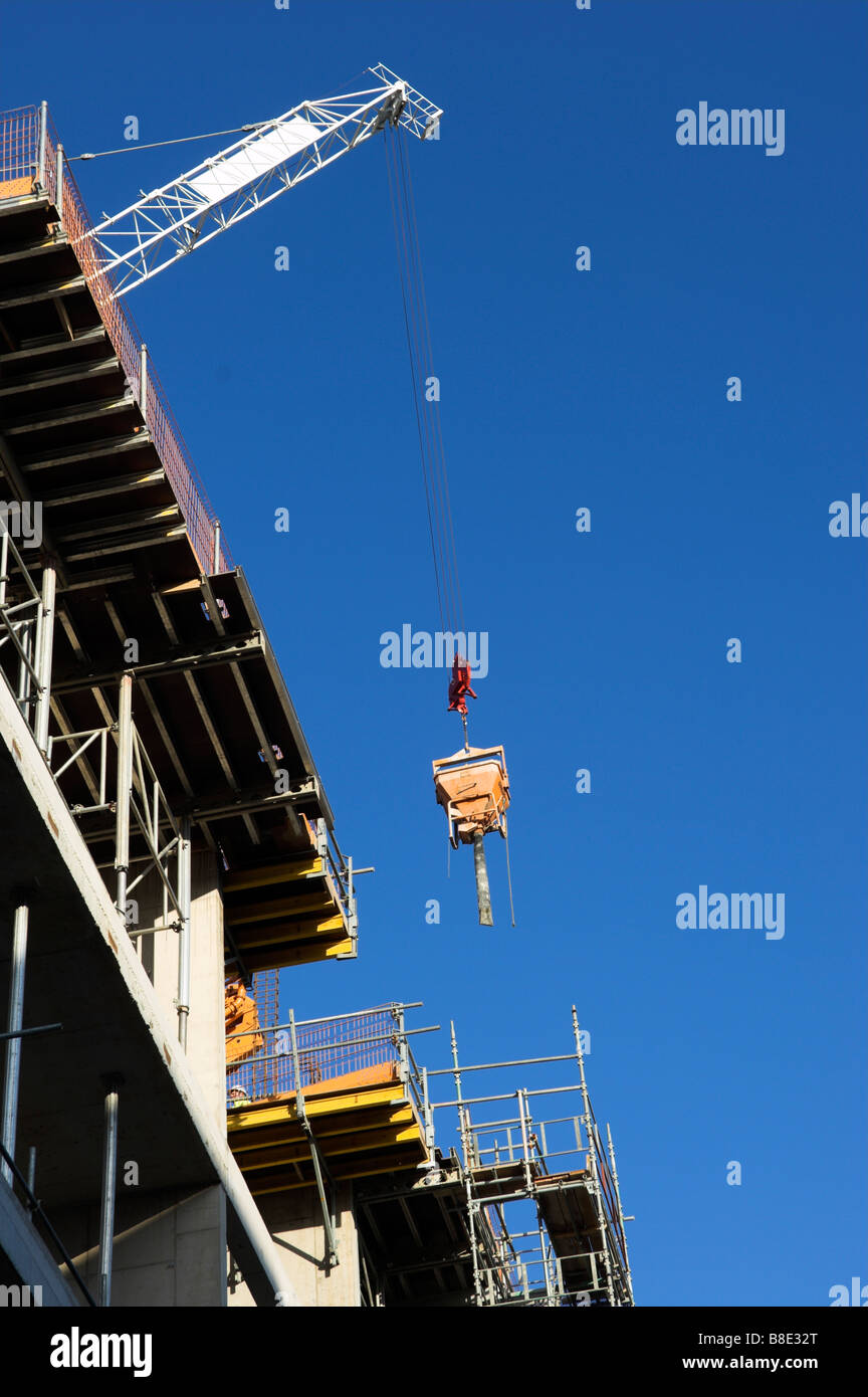 Costruzione di gru calcestruzzo abbassamento tramoggia in acciaio nuovo e un edificio in calcestruzzo Foto Stock