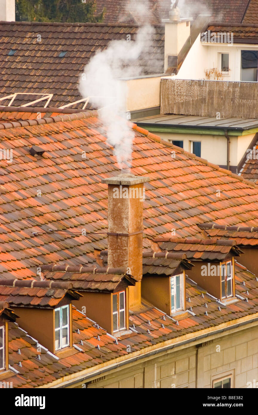 Fumo bianco dal camino e tetto di tegole rosse e cime Foto stock - Alamy