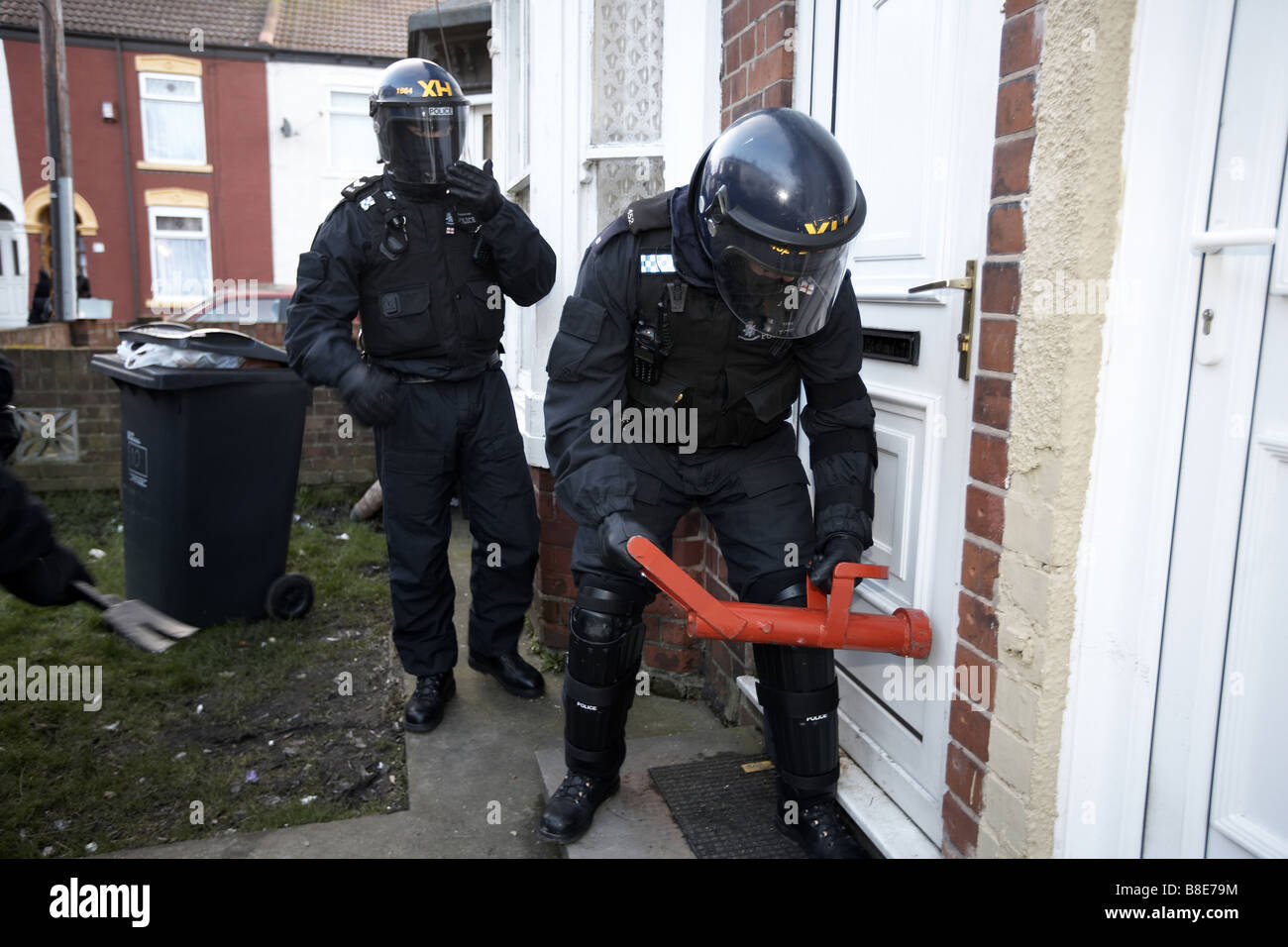 Ufficiali dal quartiere Bransholme Policing Team utilizzano un ariete per immettere una proprietà per la ricerca di farmaci, Hull, Regno Unito Foto Stock