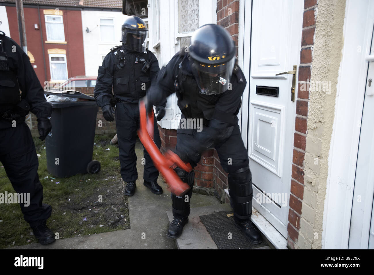 Ufficiali dal quartiere Bransholme Policing Team utilizzano un ariete per immettere una proprietà per la ricerca di farmaci, Hull, Regno Unito Foto Stock