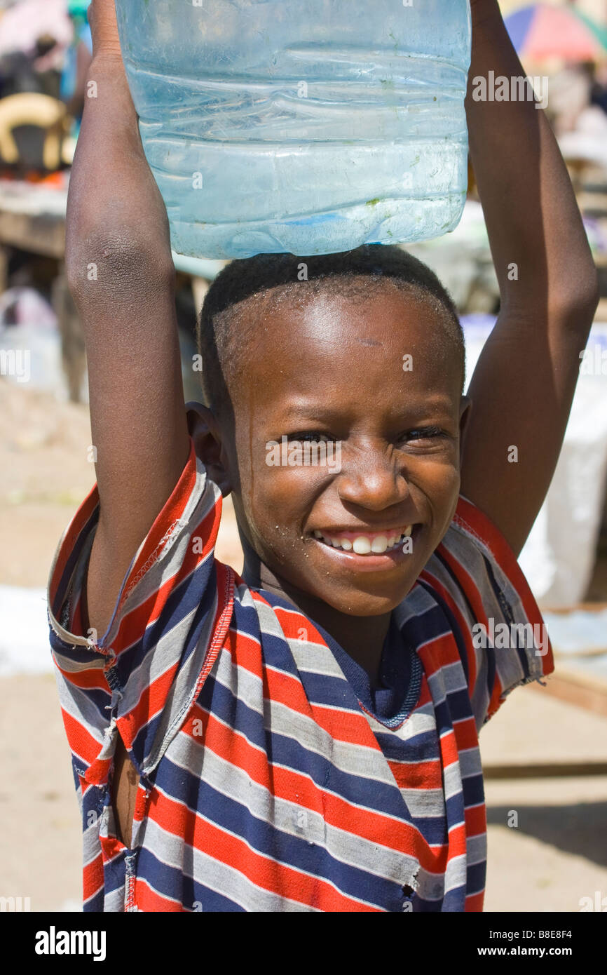 Ragazzo senegalese che trasportano l'acqua sulla sua testa a St Louis in Senegal Africa Foto Stock
