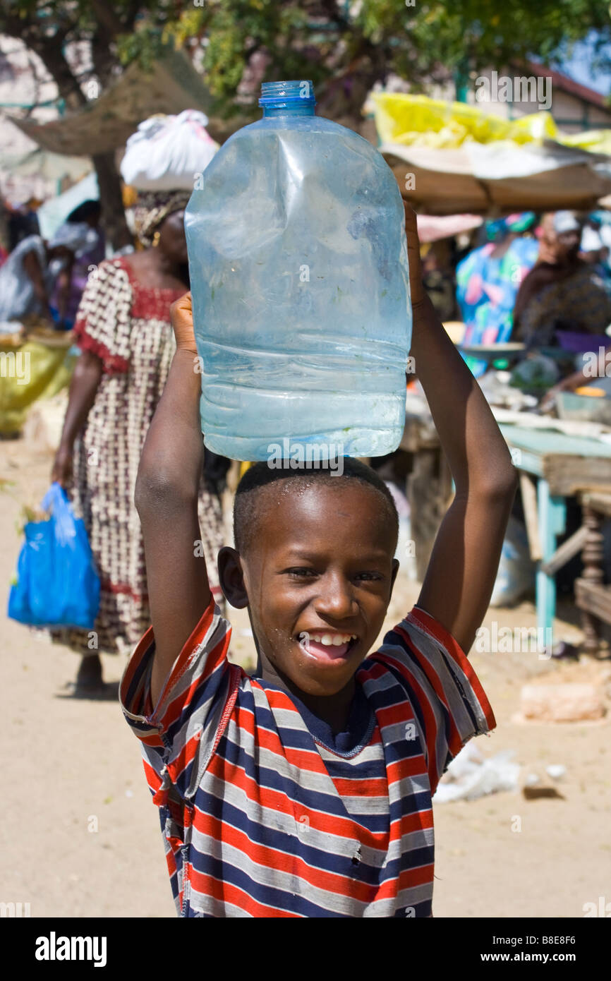 Ragazzo senegalese che trasportano l'acqua sulla sua testa a St Louis in Senegal Africa Foto Stock