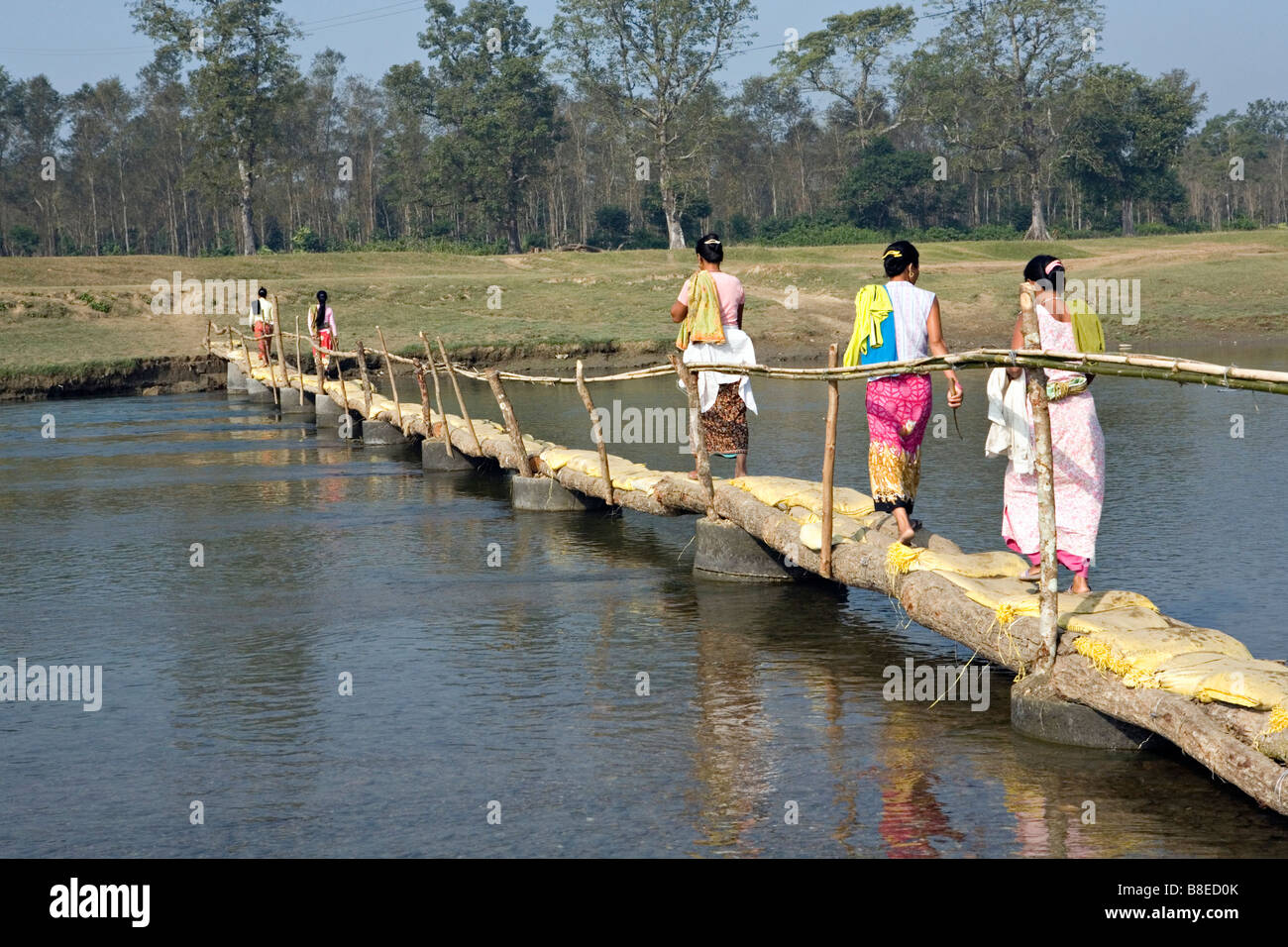 Donne locali attraversando ponte sul fiume Narayanai a Elephant Breeding Center Chitwan il parco nazionale Sauraha Nepal Foto Stock