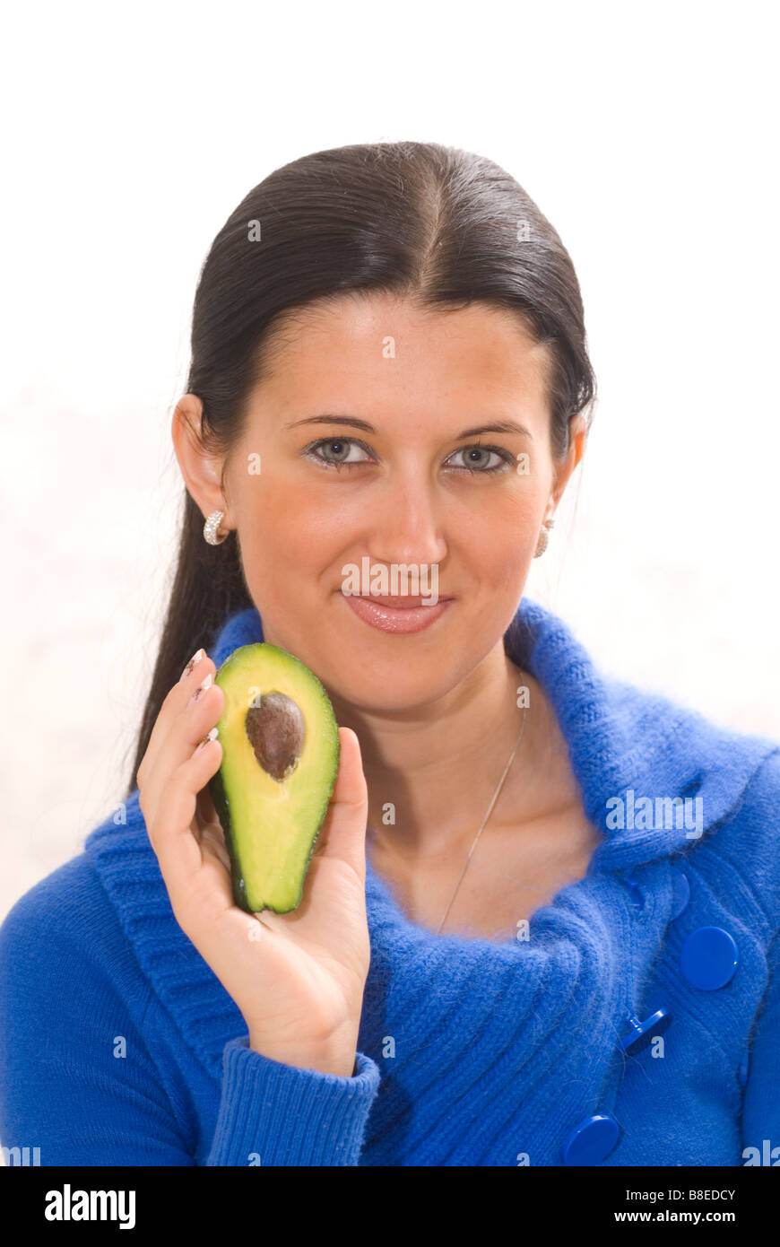Bella giovane donna tenendo un dimezzato frutto di Avocado Foto Stock