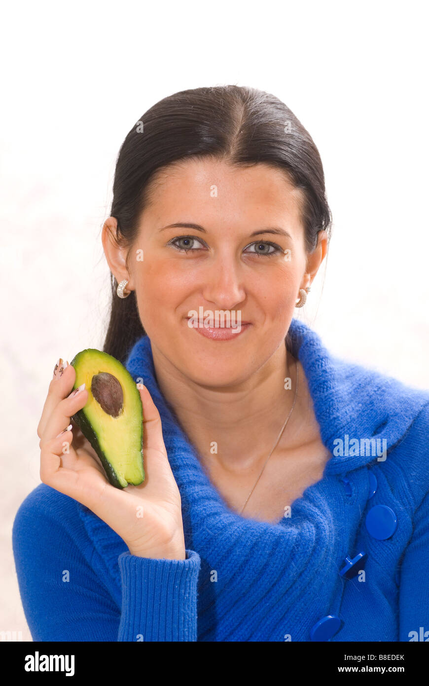 Bella giovane donna tenendo un dimezzato frutto di Avocado Foto Stock