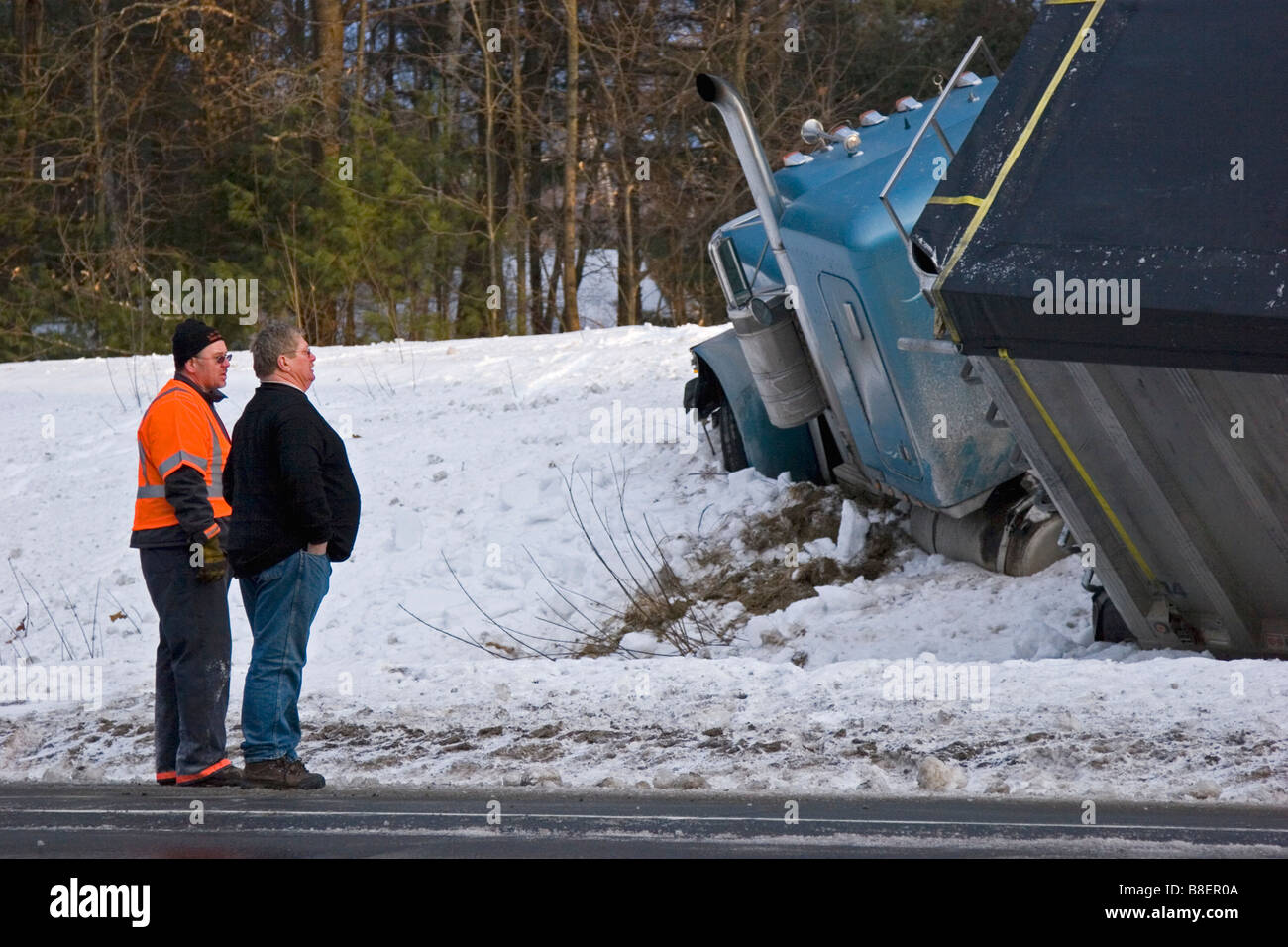 Semi carrello in fossa nella neve con gli uomini alla ricerca su Foto Stock