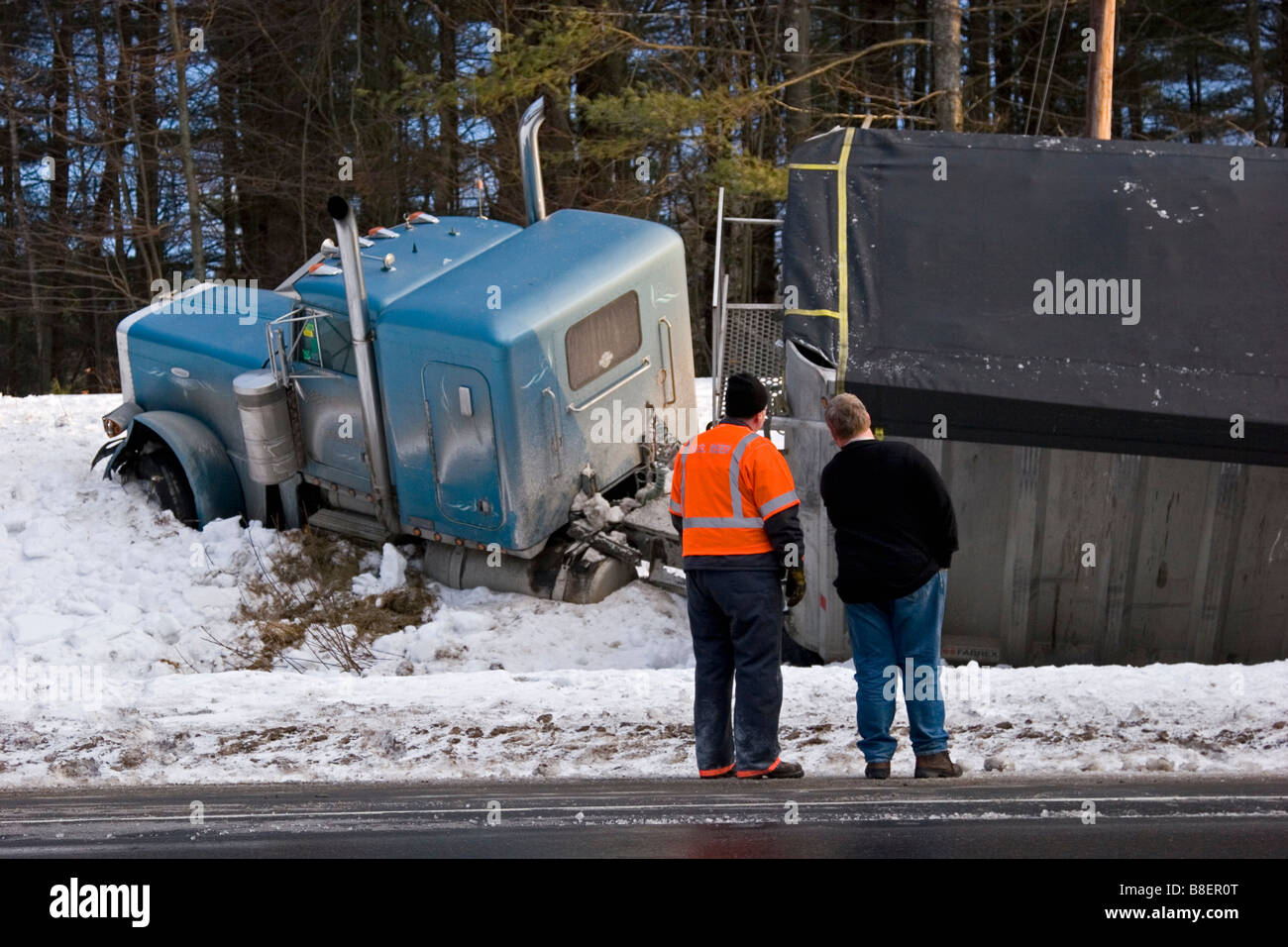 Semi carrello in fossa nella neve con gli uomini alla ricerca su Foto Stock