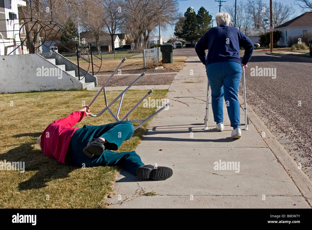Due anziani anziani a piedi utilizzando i camminatori, la donna è scattato l'uomo che è caduto giù, divertente, 1 di 4 in serie Foto Stock