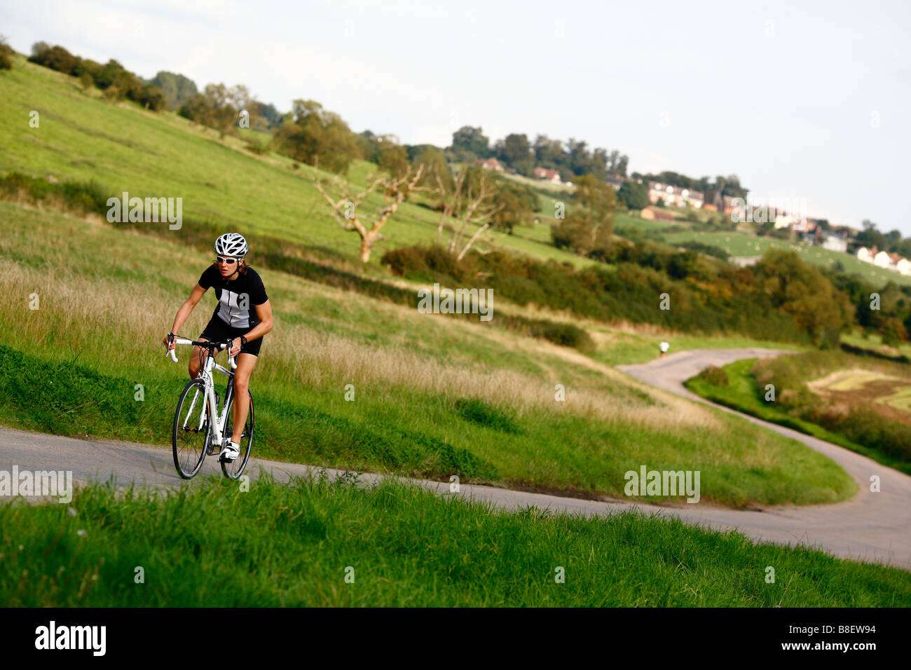 Ciclista femmina la cavalcata solitaria sulla strada di campagna Foto Stock