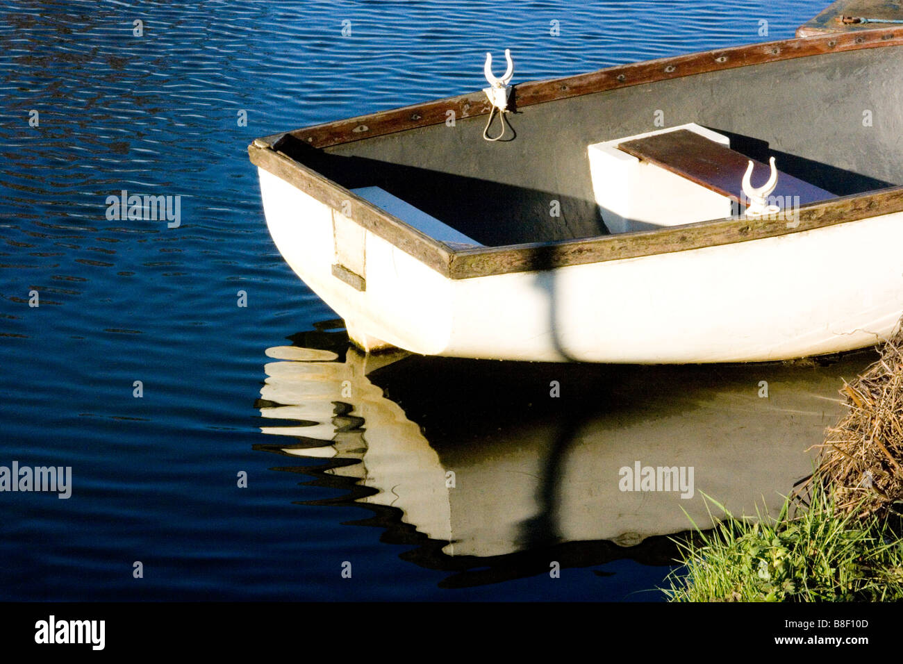 Bianco ormeggiate le barche a remi riflessa nell'acqua Foto Stock