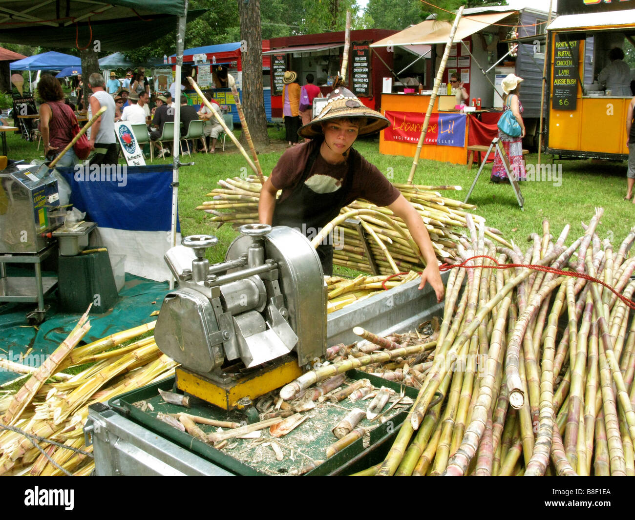 Un giovane ragazzo lavora presso la frantumazione di canna da zucchero per il succo di frutta a mercati Channon vicino a Byron Bay Australia Foto Stock