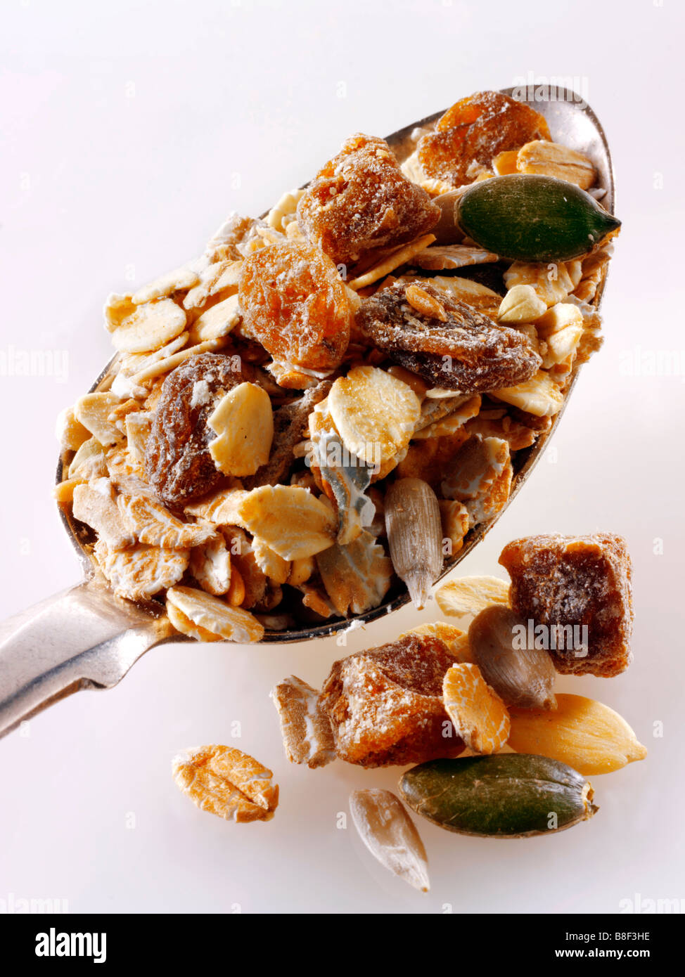 date e museli di frutta essiccati su un cucchiaio contro a. sfondo bianco Foto Stock