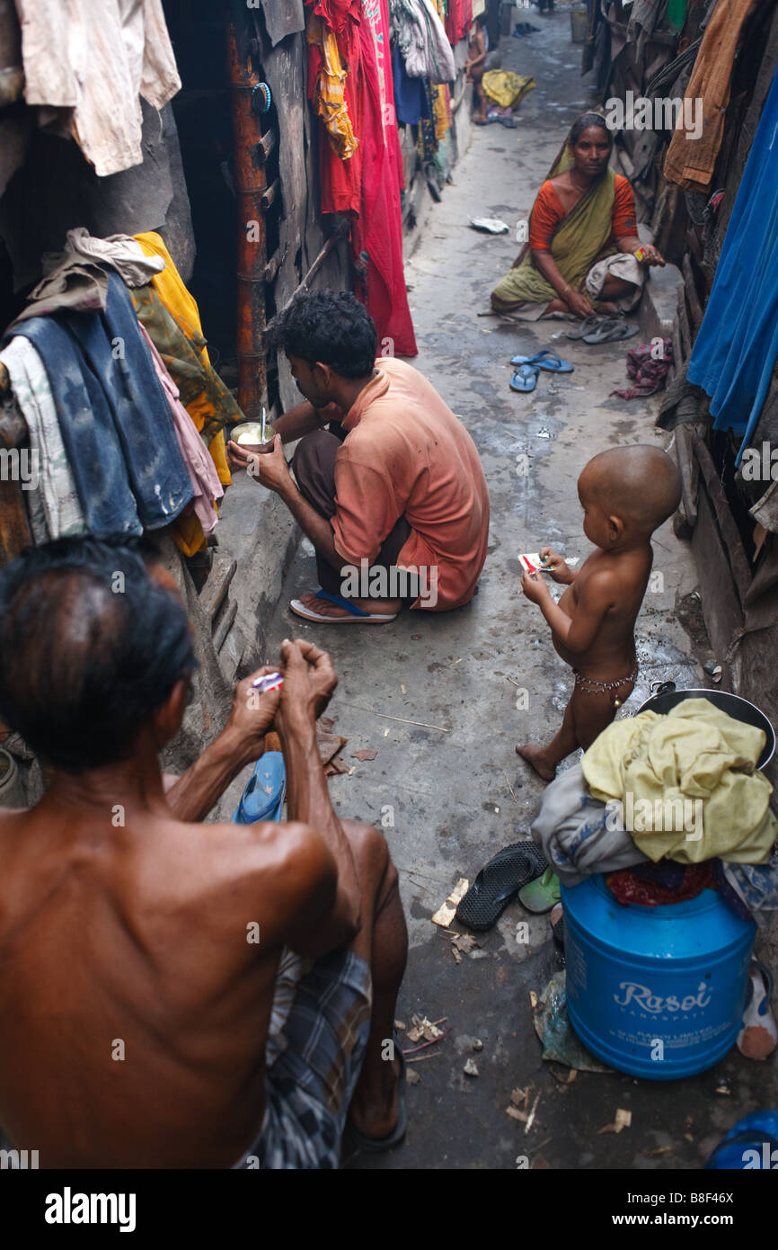 La vita quotidiana in un vicolo con bambini e famiglie in una delle baraccopoli in Kolkata, India Foto Stock