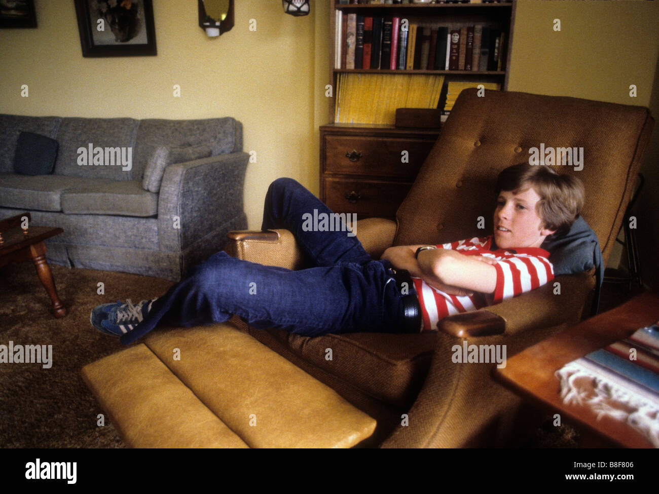 Bianco giovane ragazzo teen riposa nella grande poltrona reclinabile sedia con piedi Foto Stock