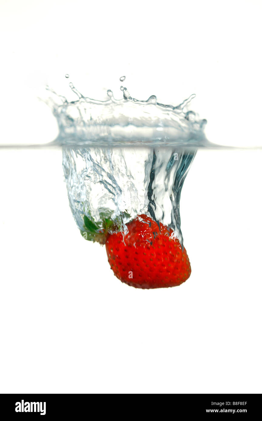 Fragole mature cadere in acqua Foto Stock