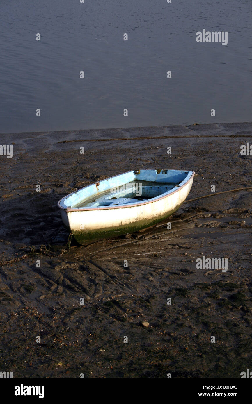 Una vecchia barca a remi a bassa marea su una spiaggia fangosa. Foto Stock