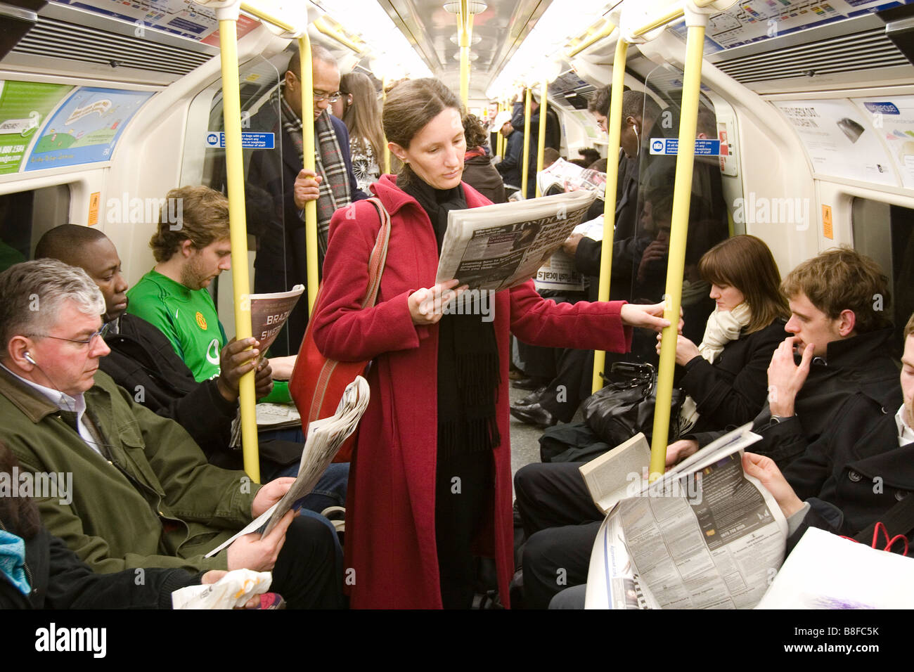 Persone che leggono quotidiani sulla metropolitana di Londra. Foto Stock