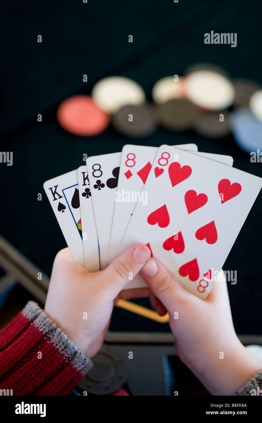 Un giovane bambino tiene un full house mano di poker Foto Stock