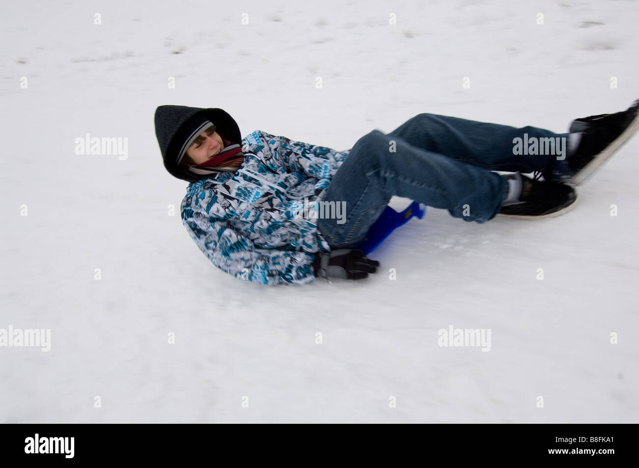 Gli adolescenti divertirsi in slittino sulla neve su una slitta improvvisata Foto Stock