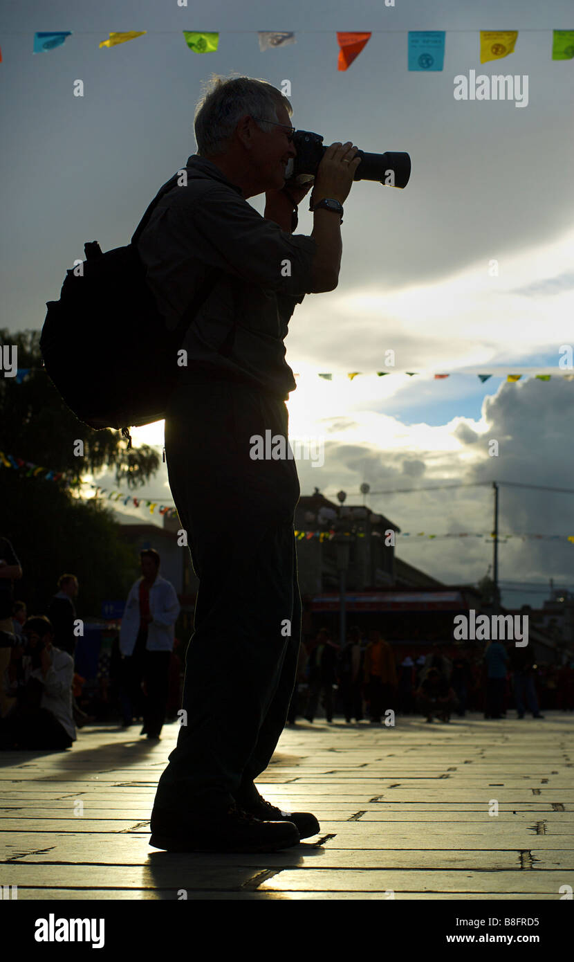 Silhouette di un fotografo con una telecamera professionale la composizione di una fotografia. Barkor Square, Tibet Foto Stock